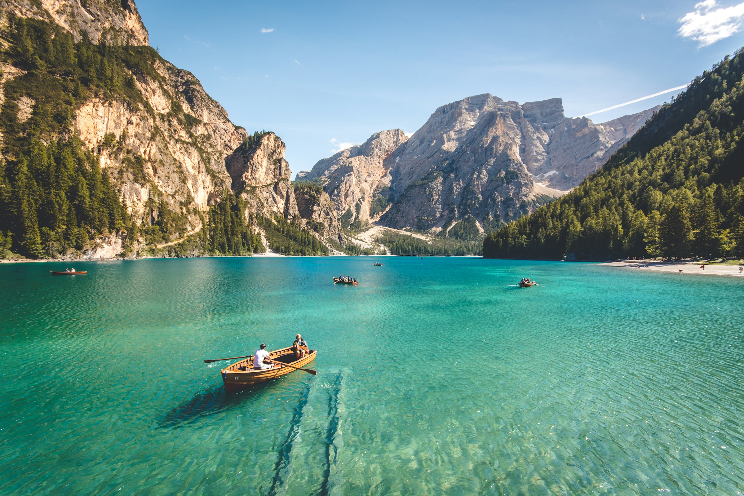 Türkisfarbener Bergsee, Holzboote und Gipfel unter klarem Himmel