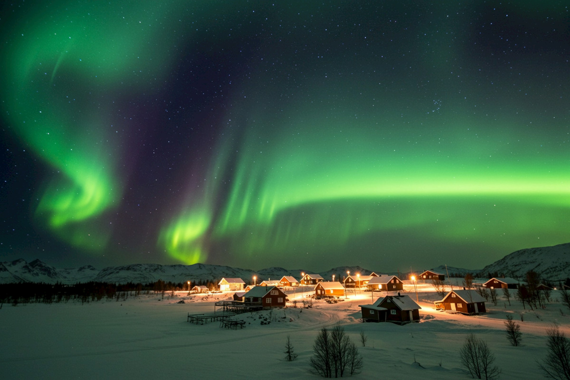 Curtain of northern lights above a snow-covered village